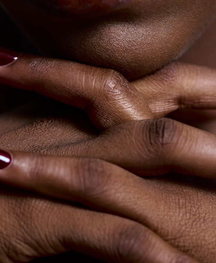 Massage + Essen Häuserfüße eines Menschen mit dunkler Hautfarbe und Nagellack auf den Nägeln.